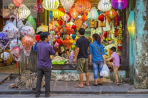 Menschen betrachten Seidenlaternen zum Verkauf auf der Straße in Hoi An