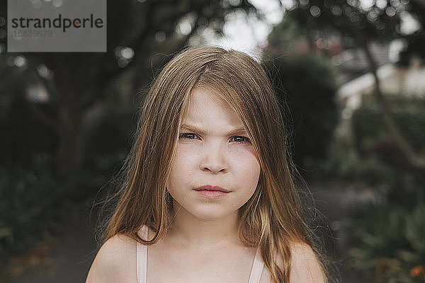 Porträt eines jungen Mädchens mit ernstem Gesicht im Freien stehend