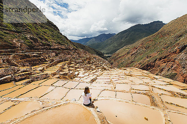 Junge Frau sitzt in der Nähe der berühmten Salzminen in Peru