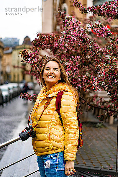 Junge Touristin mit Kamera lächelt in der europäischen Altstadt