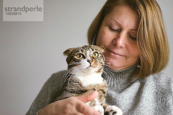 Frau hält schöne Katze auf weißem Hintergrund