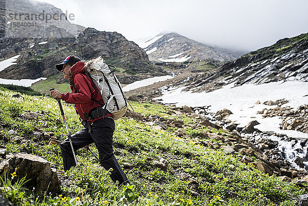 Junge entschlossene Frau wandert in den Bergen bergauf