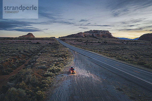 Einsame Straße in Utah am Abend mit einem angehaltenen Auto