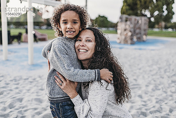 Nahaufnahme eines Porträts von Mutter und Sohn  die in der Dämmerung auf dem Spielplatz lächeln