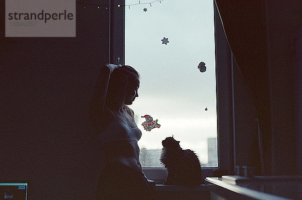 Eine Frau steht vor einem Fenster in einer Wohnung