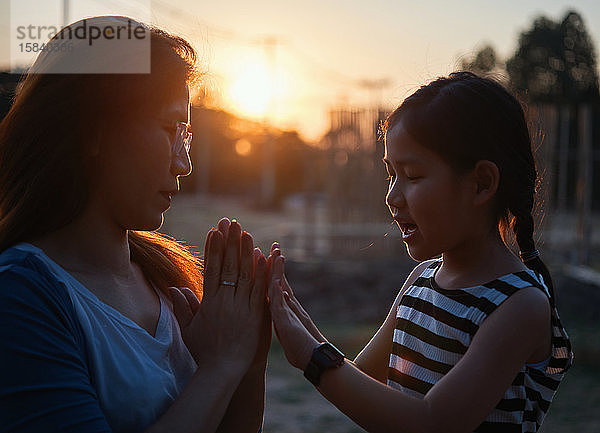 Mutter und Tochter spielen bei Sonnenuntergang zusammen