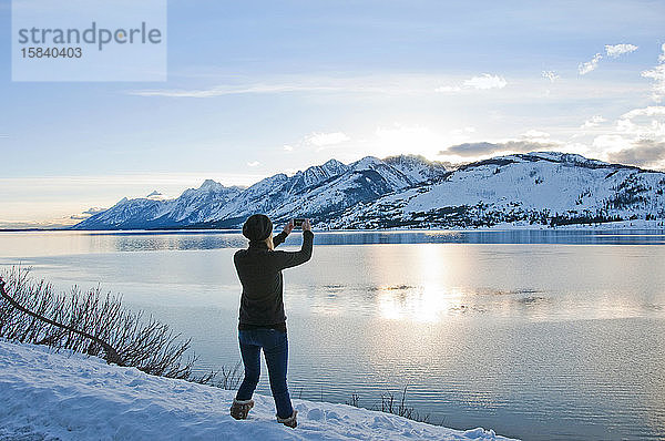 Frau macht ein Foto mit einem Smartphone von Jackson Lake und Teton Range