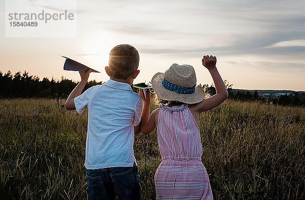 Bruder und Schwester schauen in die Ferne und spielen bei Sonnenuntergang