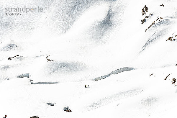 Zwei nicht erkennbare Personen in verschneiten Bergen beim Wintersport