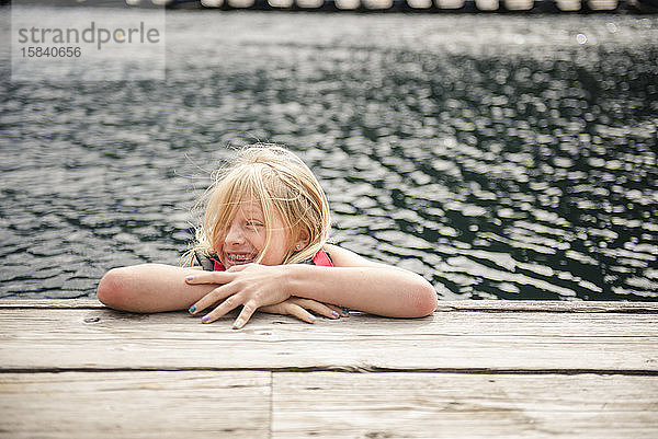 Junge Mädchen lachend und schwimmend am Dock