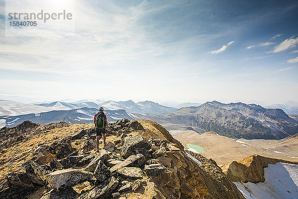 Rucksacktourist nähert sich Berggipfel mit Aussicht.