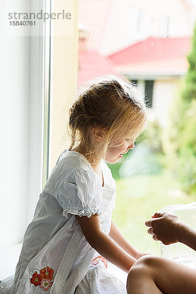 Kleines Mädchen spielt am Fenster