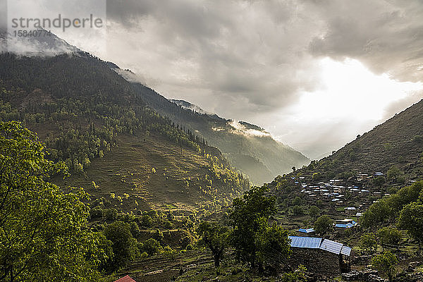 Landschaft mit grünem Bergtal und Dorf bei Sonnenuntergang in Nepal