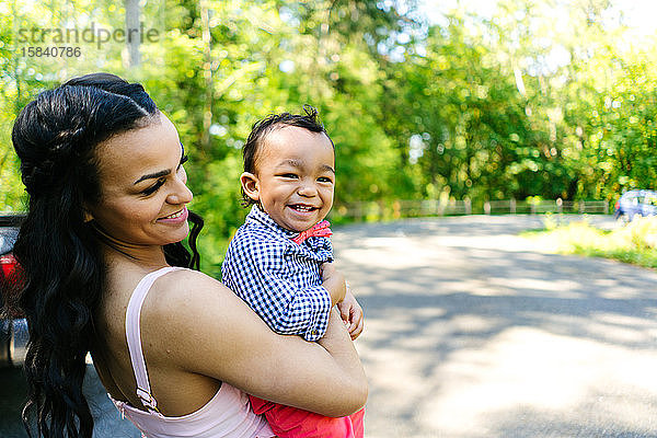 Eine Mutter und ihr kleiner Sohn stehen an einem warmen Sommertag gemeinsam in einem Park