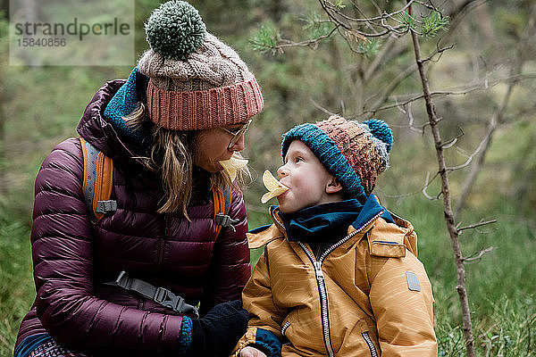 Mama und ihr Sohn machen beim Essen und Wandern im Winter alberne Gesichter