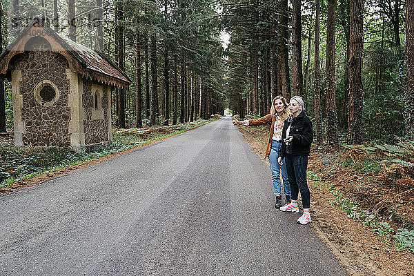 Zwei Frauen trampen auf einer Waldstraße in Frankreich