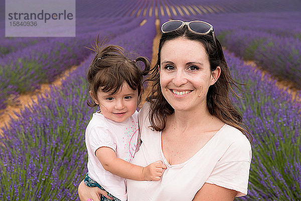 Mutter und Tochter spazieren im Sommer zwischen Lavendelfeldern