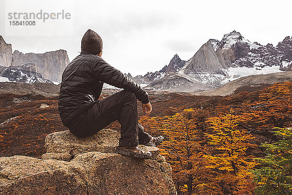 Wanderer  der im Herbst in den Bergen auf Steinen sitzt