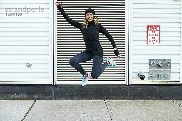 Eine glückliche athletische Frau springt.