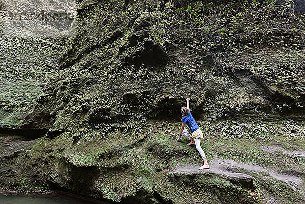 Kletterndes Mädchen auf grüner Klippe