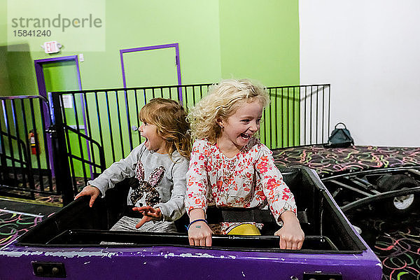 zwei kleine Mädchen  die auf der Achterbahn vor Freude lachen