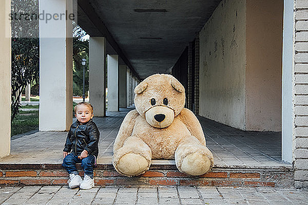 Ein kleiner Junge spielt mit einem riesigen Teddybären.