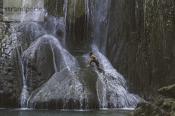 Mann klettert auf Wasserfall