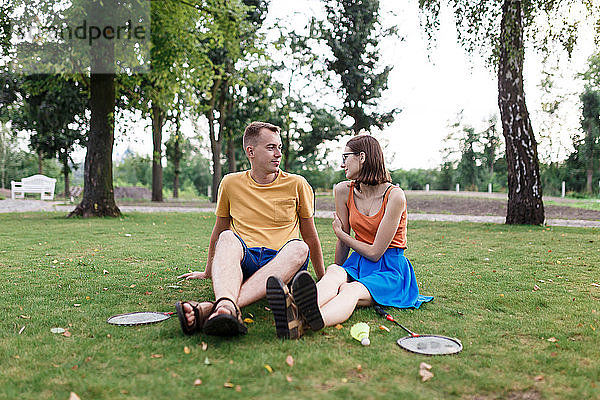 Tausendjähriges Ehepaar sitzt im Gras  nachdem es im Park Badminton gespielt hat