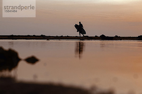 Silhouette eines Surfers bei Sonnenuntergang am Strand