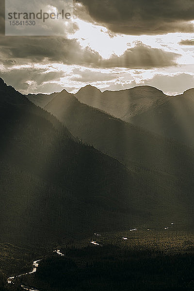 Goldenes Licht bricht durch Wolken in ein wunderschönes Bergtal