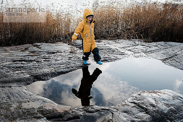 Junge und sein Spiegelbild springen über Wasser auf einer Insel in Schweden