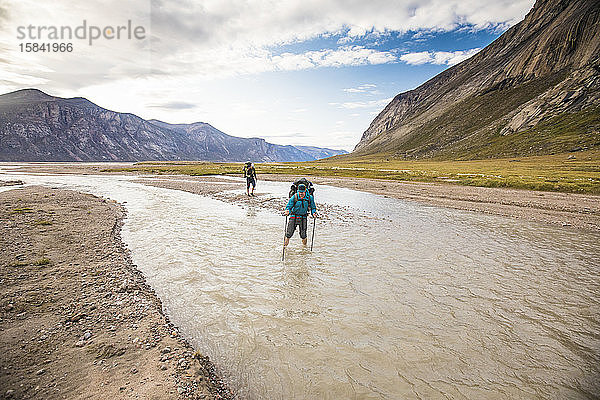 Zwei Rucksacktouristen überqueren Fluss auf Baffin Island.