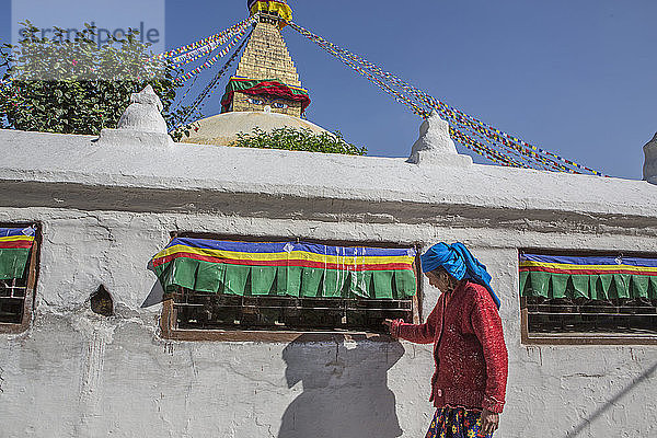 Eine Frau dreht buddhistische Gebetsmühlen an der Boudhanath-Stupa in Kathmandu.