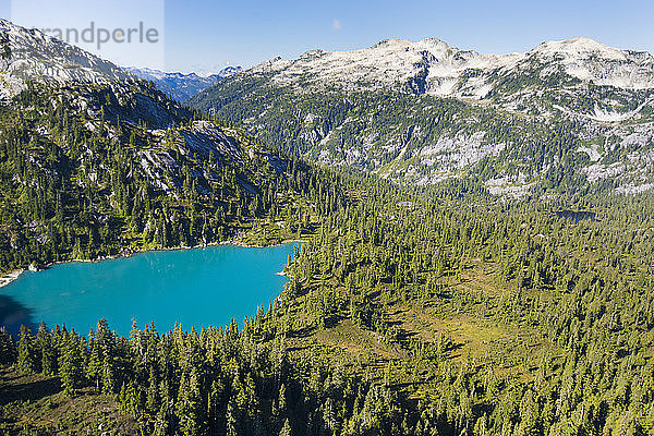 Luftaufnahme des türkisfarbenen Sees in einer Bergkulisse.