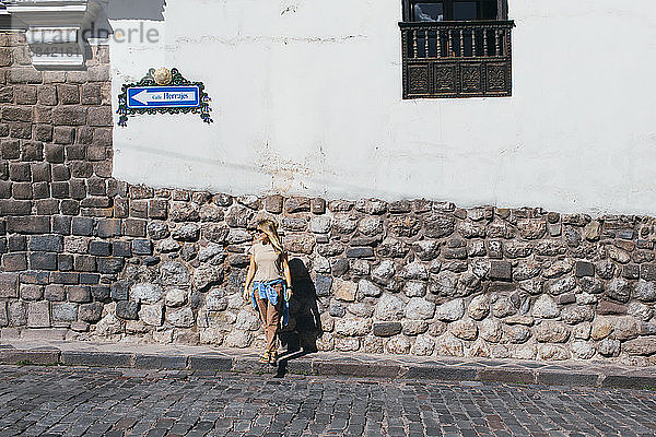 Eine junge Frau steht an einer weißen Wand in Cusco  Peru