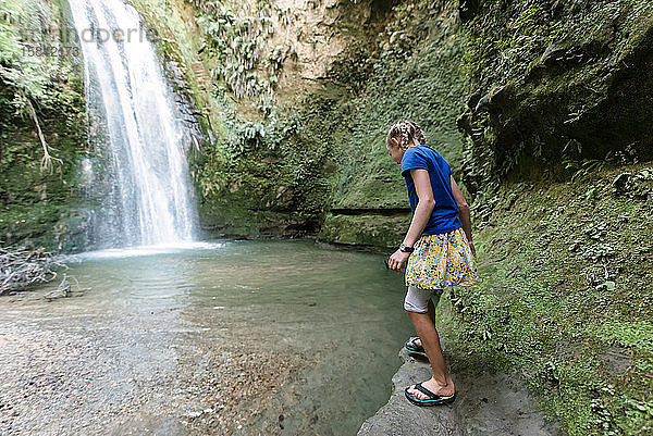 Ein Mädchen steht auf einer Klippe und schaut ins Wasser