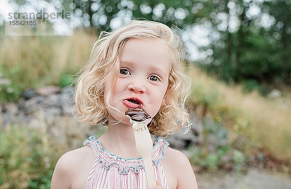 lustiges Porträt eines jungen Mädchens  das Schokolade und Marshmallows isst