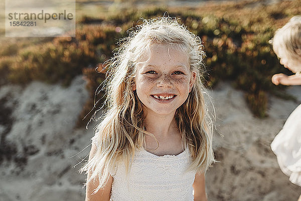 Porträt eines jungen Mädchens im Schulalter mit Sommersprossen  das in die Kamera lächelt