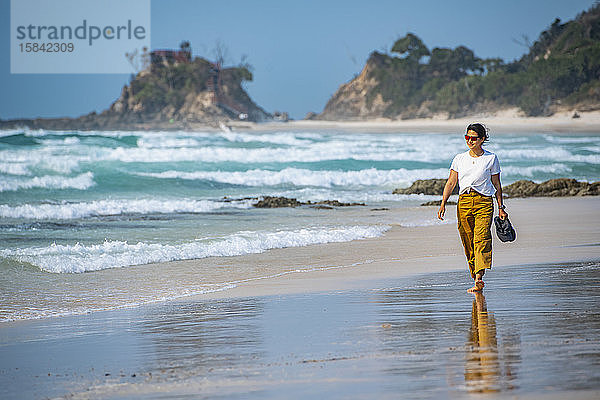 Frau geht barfuss am Strand von Byron Bay / Australien