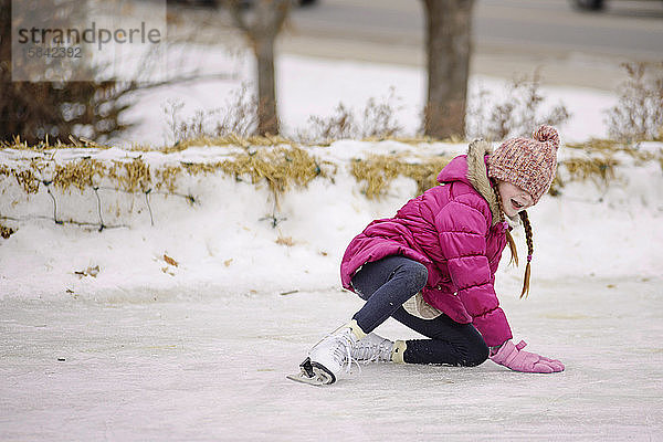 Kleines Mädchen stürzt beim Schlittschuhlaufen
