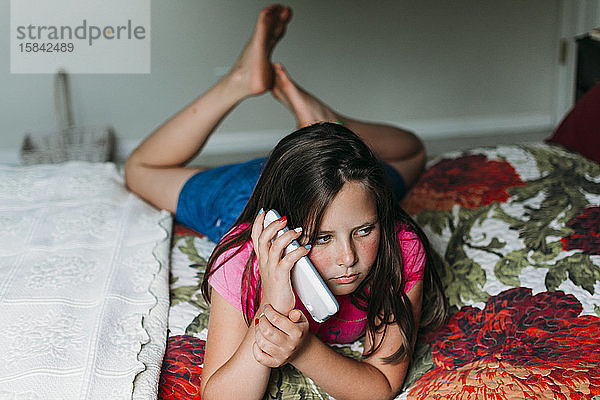 Teenager-Mädchen entspannt sich im Bett und spricht mit ihrem Handy