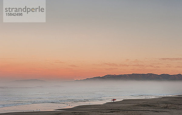 einsamer Surfer kontrolliert Surfen bei Sonnenaufgang in Kalifornien