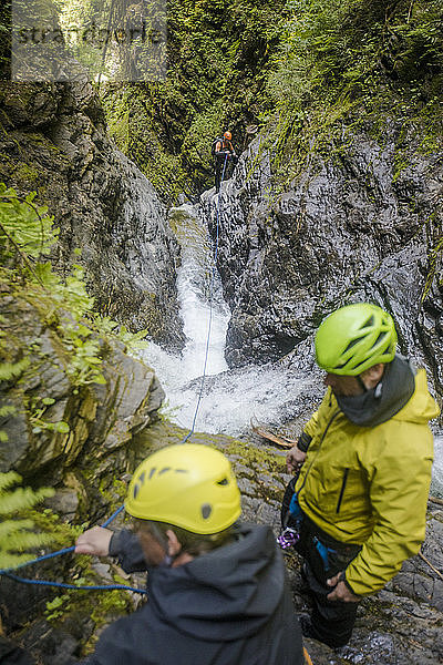 Drei Männer bauten eine Sicherung auf und befestigten eine Leine  um einen Slotcanyon sicher zu überqueren.