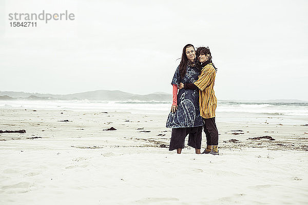 Gleichgeschlechtliches lesbisches Paar umarmt sich bei wildem Strandabenteuer im Wind
