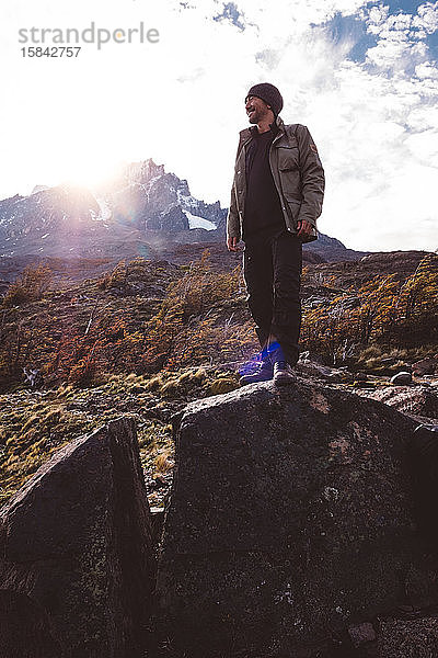 Glücklicher Wanderer steht auf Stein in den Bergen
