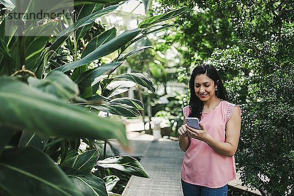 Hübsches Mädchen überprüft ihr Handy im Gewächshaus