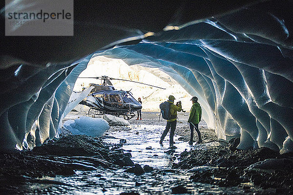 Mann fotografiert Partner in Eishöhle während Hubschrauberflug.