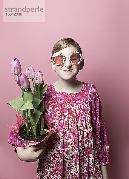 Mod  schrulliges Mädchen  helle Haut  hält rosa Tulpen auf rosa Hintergrund