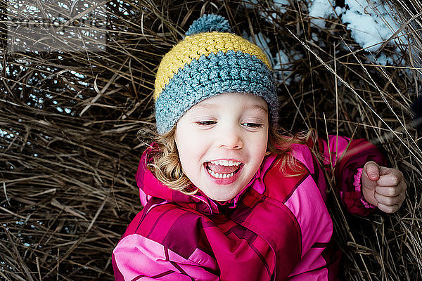 Nahaufnahme eines jungen Mädchens  das draußen im Schnee auf dem Boden spielt