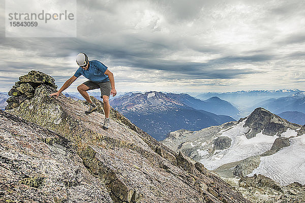 Bergsteiger wandert vorsichtig vom Gipfel eines Berges.